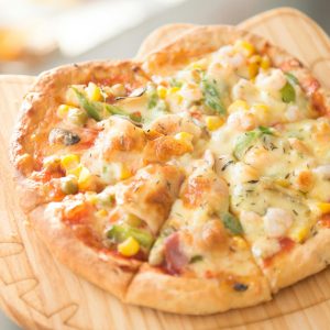 Fresh homemade vegetable pizza topped with cheese and served on a wooden board, perfect for a gourmet meal.